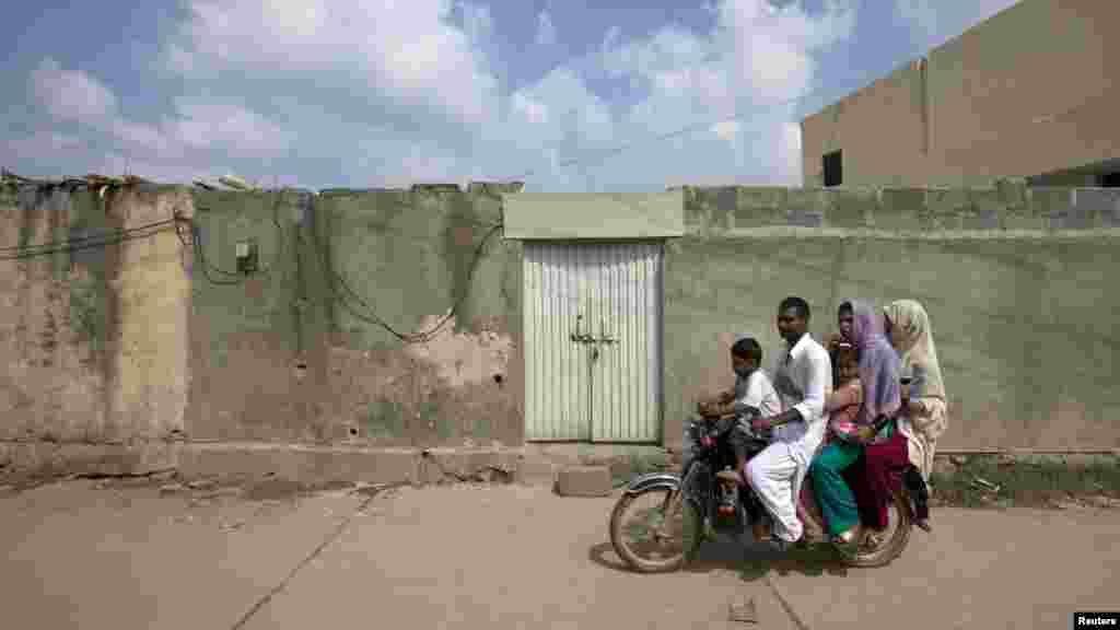 A family rides past the locked house of Rimsha Masih, a Down syndrome Christian girl accused of blasphemy, on the outskirts of the Pakistani capital, Islamabad, on August 23. (REUTERS/Faisal Mahmood)