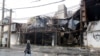 An Iranian woman walk past next to a shopping center that was burned during the protests over increasing fuel price by government in city of Shahriar, Alborz province, November 20, 2019