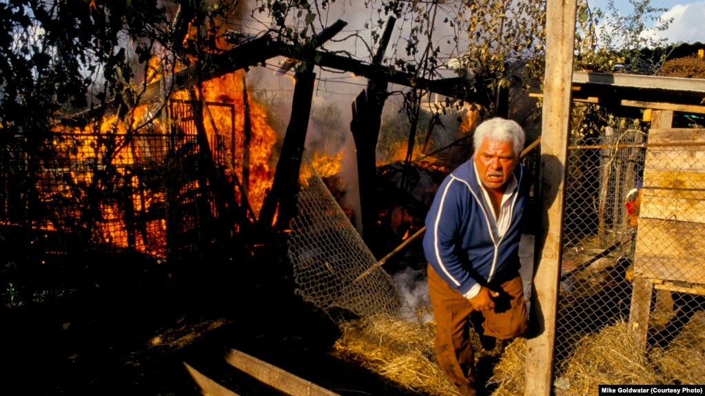 ოჩამჩირე, 1993 წლის 28 სექტემბერი: მამაკაცი ცდილობს ცეცხლის ჩაქრობას აფხაზეთის სეპარატისტული ძალების სარაკეტო თავდასხმის შემდეგ, სოხუმის დაცემის მეორე დღეს.