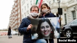 Richard Ratcliffe holds a a picture of his wife, Nazanin Zaghari Ratcliffe, as he and their daughter attend a protest outside the Iranian Embassy in London. (file photo)