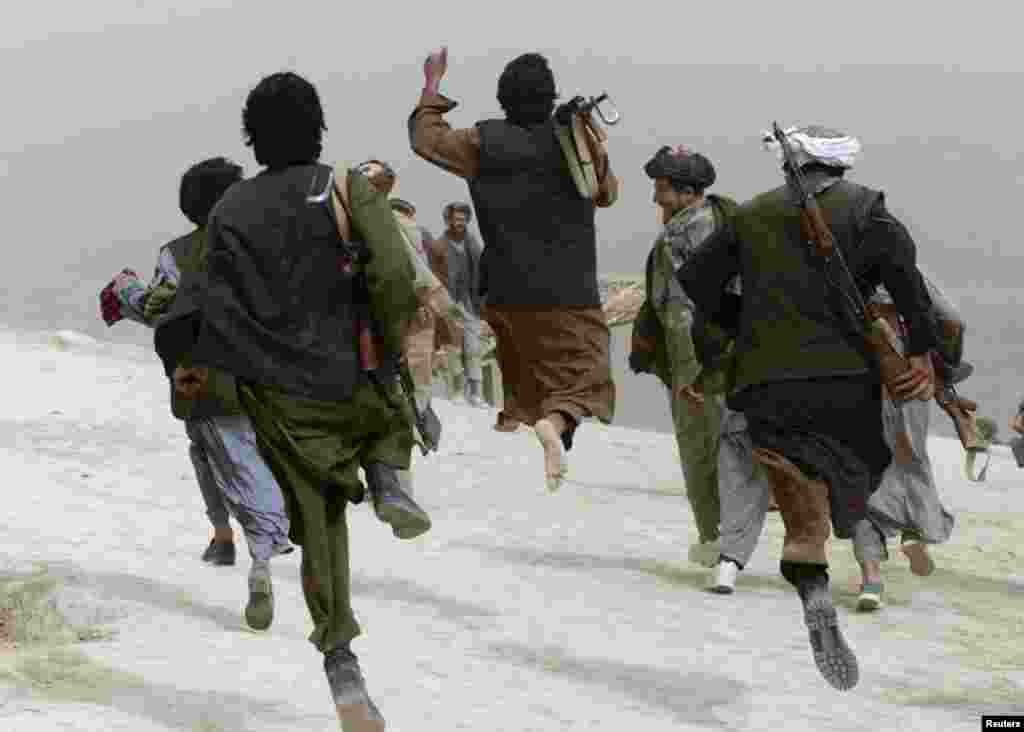 Afghan opposition Northern Alliance soldiers run and jump as they return from a frontline position after battle near the town of Charatoy in the days after the U.S.-led response to 9/11 began in Afghanistan.