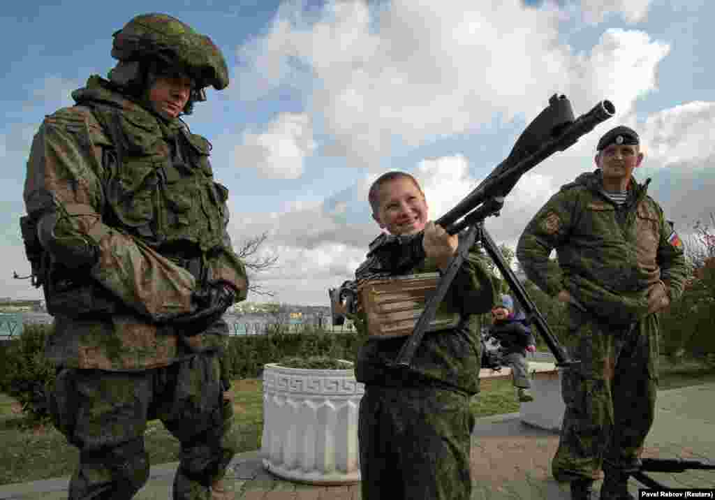 A boy holds a weapon at a military exhibition during for new recruits of Yunarmiya in Sevastopol.