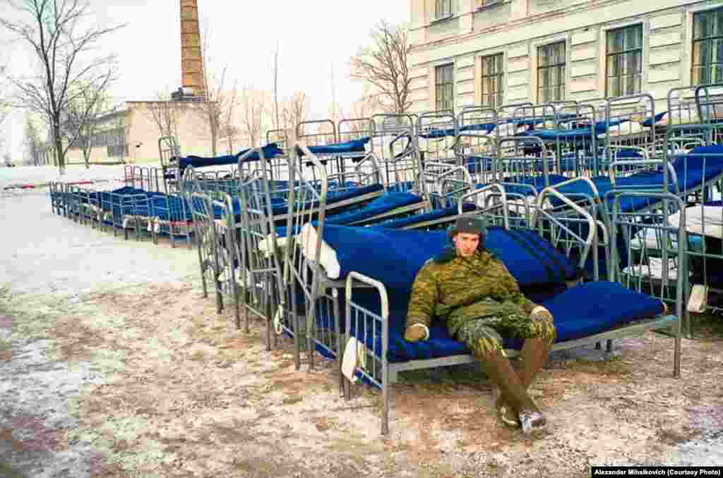 A soldier guards his bed, which he dragged outside during a fire alarm.