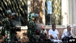 Chinese riot police march pass local Uyghur residents near a mosque just before Friday prayers in Urumqi in July 2009, soon after the height of the Han-Uyghur violence.