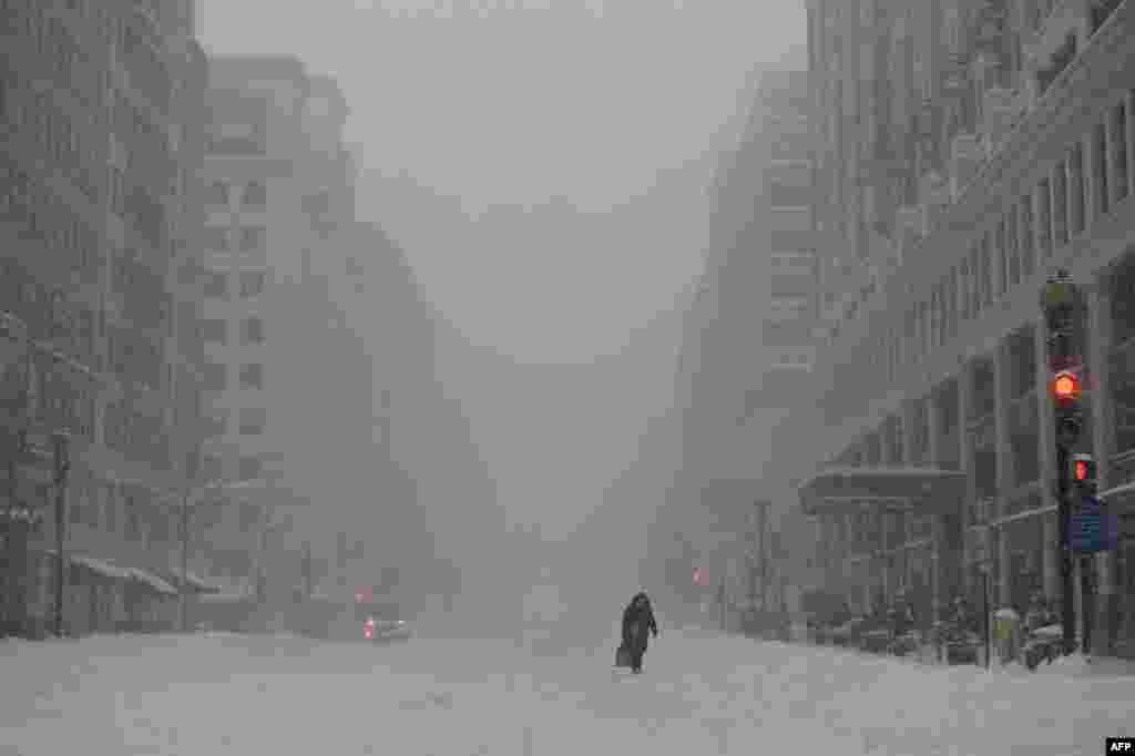 Женщина идет по 13-й улице в Нью-Йорке, по которой из-за снежного шторма было остановлено движение общественного транспорта