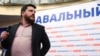 Леонид Волков на фоне баннера избирательной кампании Алексея Навального