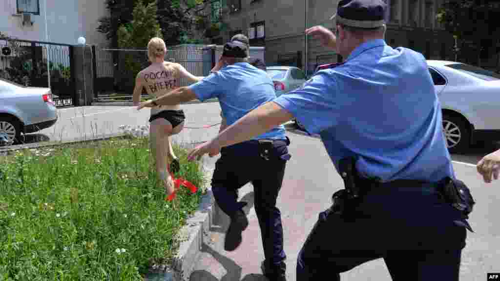 Kiyevdə polis əməkdaşları məşhur qadın təşkilatı Femen-in kürəyində &quot;Rusiya, irəli!&quot; şüarı yazılan fəalını tutmağa çalışırlar. 7 iyun 2013
