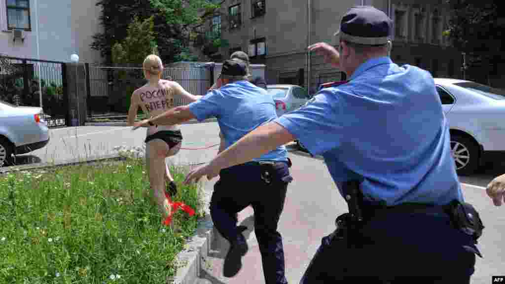 Ukrajina - Članica ženske feminističke organizacije Femen s riječima "Naprijed Rusija!" ispisanim na leđima bježi od policajaca vičući: "Vladimire, volim te!",Kijev, 7. juni 2013. Foto: AFP / Sergei Supinsky 