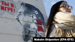 A woman walks past a mural with soccer-related motifs in Moscow.