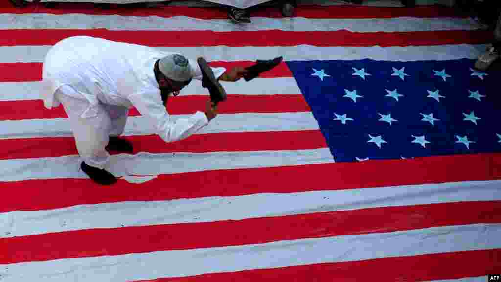 An activist of Pakistan's Jamaat-ud-Dawa group beats a U.S. flag with his shoes during a protest rally in Karachi over a U.S. bounty offer for an Islamist militant. (AFP/Asif Hassan)