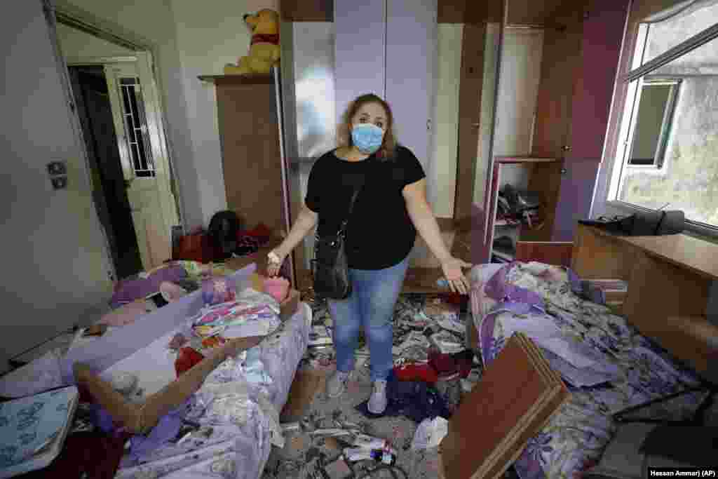 Mona Al Chami, poses for a photograph inside her destroyed apartment after Tuesday's explosion in the seaport of Beirut, Lebanon, Thursday, Aug. 6, 2020.