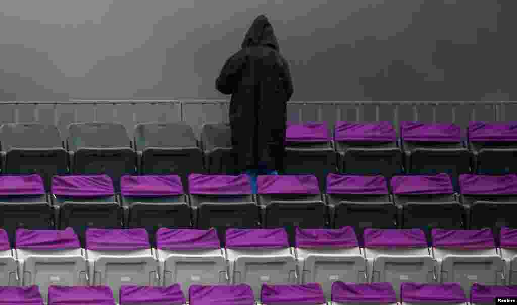 A spectator faces dark clouds next to empty seats in the bleachers before the trial round of the large-hill ski-jumping portion of the nordic combined individual Gundersen 10-kilometer event. (Reuters/Michael Dalder)