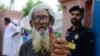 An elderly Pakistani man shows his inked thump after casting his vote outside a polling station during general election in Lahore on July 25.