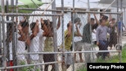 Asylum seekers stand behind a fence at the Manus Island detention centre in Papua New Guinea. There are currently 916 refugees and asylum seekers in the Australian-run facility