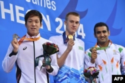 Казахстанский спортсмен Дмитрий Баландин (в центре) показывает золотую медаль. Инчхон, 26 сентября 2014 года.