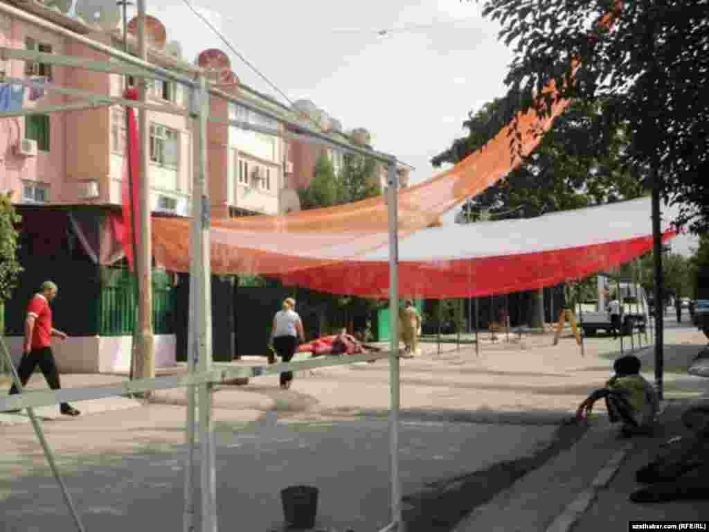 Adamlar gijeki toýdan ozal ýaşaýyş jaýynyň öňündäki meýdançany bezeýärler.