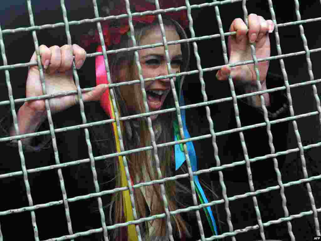 An activist of Ukrainian women's movement FEMEN shouts from a police car after she was arrested during the protest action "Italia is not a bordello" in front of the Italian Embassy in Kyiv on February 14. The young Ukrainians support thousands of Italian women in their protests at "degrading" media coverage of the recent sex scandals surrounding Italian Prime Minister Silvio Berlusconi. Photo by Sergei Supinsky for AFP