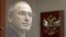 Former oil tycoon Mikhail Khodorkovsky stands behind a glass wall before the start of a court session in Moscow, in October 2010.