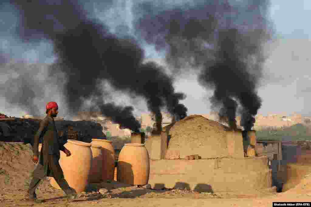 A man stands near smoke billowing from a brick kiln in Karachi, Pakistan. (epa-EFE/Shahzaib Akber)