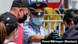 Местные жители и сотрудник полиции в защитных масках на блокпосту на въезде в Алматы. 11 мая 2020 года.