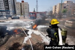 Израильские спасатели на месте взрыва выпущенной из Газы ракеты, упавшей на улице в Ашкелоне