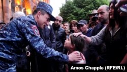 A young girl is comforted by a police officer during the Armenian protests in Yerevan, April 2018. (Amos Chapple, RFE/RL)