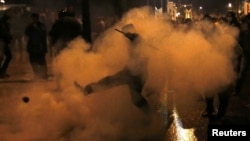 A protester kicks away a gas canister during clashes with riot police during a 48-hour strike by the two major Greek unions in central Athens on November 7.