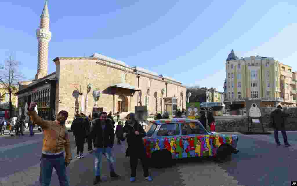 People take selfies in Plovdiv with a painted Trabant. The East German car is on display as part of Art Liberty, a traveling exhibition marking the 30th anniversary of the fall of the Berlin Wall.