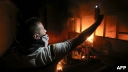 An Iraqi protester takes a selfie while standing outside the burning headquarters of the Iranian Consulate in the southern city of Basra on September 7.