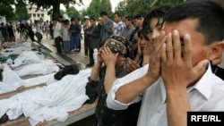 People pray near the bodies of victims of a massacre in the Uzbek city of Andijon in 2005 that left hundreds dead. 