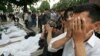 Люди молятся около тел жертв расстрела в Андижане. 14 мая 2005 года.
