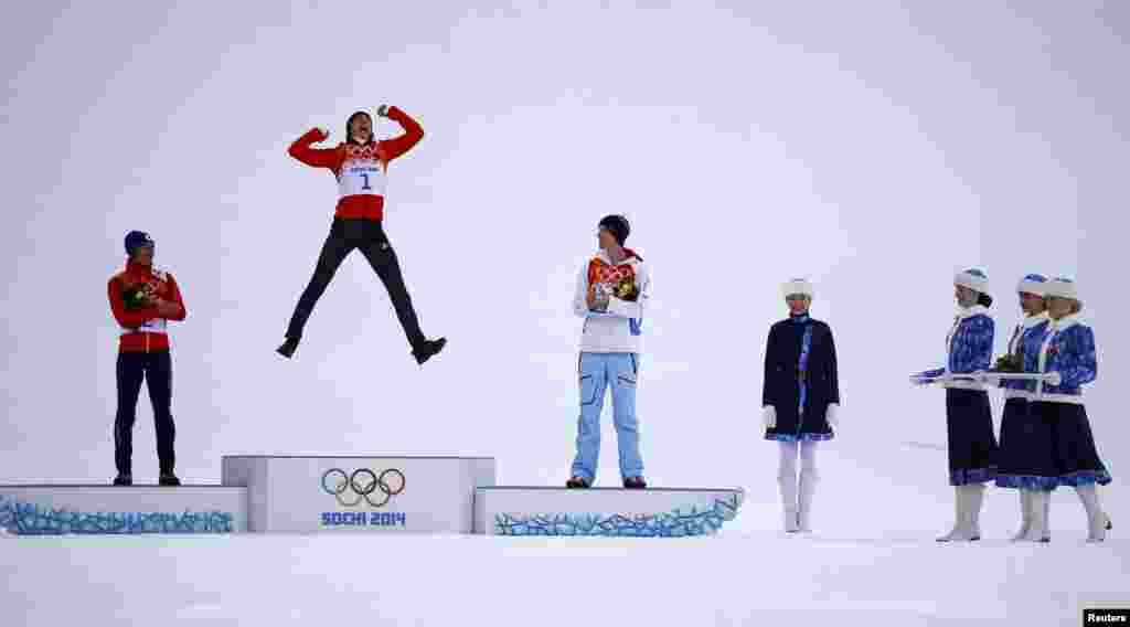 Winner Eric Frenzel of Germany jumps on the podium as second-placed Japan&#39;s Akito Watabe (left) and third-placed Norway&#39;s Magnus Krog applaud during the flower ceremony for the nordic-combined individual normal hill/10-kilometer event.