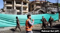 Afghan security forces in front of damaged buildings on May 9, a day after the deadly attack in Kabul against Counterpart International.