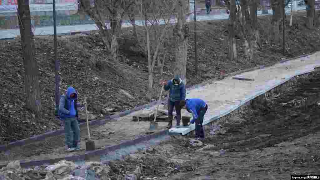 Рабочие бетонируют бордюры на левом берегу Салгира в районе улицы Воровского