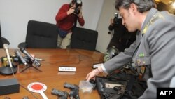 Italian authorities display guns, bullets, and other weapons during a press conference announcing the arrests.