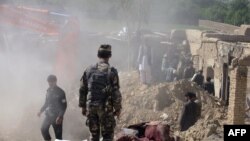 Afghan security forces inspect the site of a blast at a police arms depot in Kandahar on April 21.