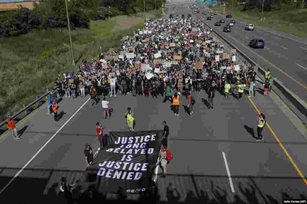 Demonstrators march on pavement, Sunday, May 31, 2020, in Minneapolis. Protests continued following the death of George Floyd, who died after being restrained by Minneapolis police officers on May 25. (AP Photo/Julio Cortez)