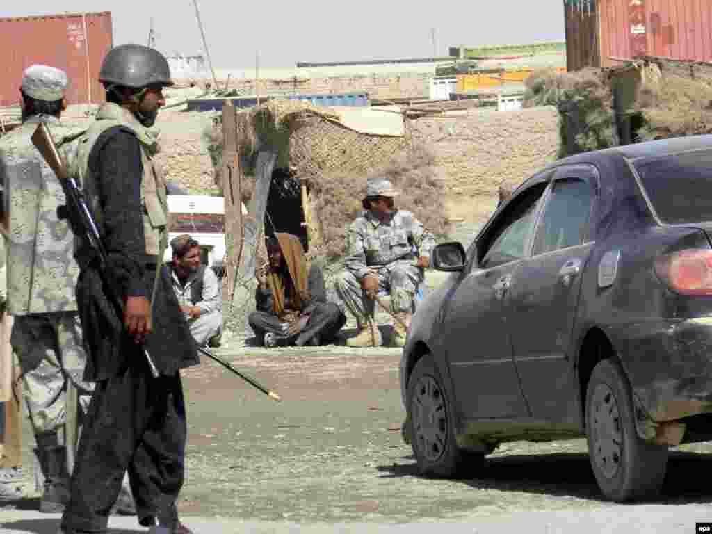 Pakistan -- Pakistani (L) and Afghan (behind) border security force personnel stand alert at their respective sides of the border, at Pakistani Chaman border along Afghanistan, 18Oct2009 - Caption: epa01901630 Pakistani (L) and Afghan (behind) border security force personnel stand alert at their respective sides of the border, at Pakistani Chaman border along Afghanistan, 18 October 2009. Security across the country has been intensified after Pakistani security forces have started a much-awaited ground offensive against Taliban and al-Qaeda insurgents in the lawless South Waziristan tribal region along the Afghan border.