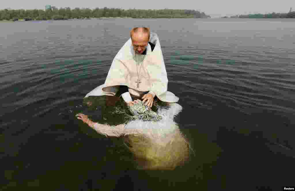 A Russian Orthodox priest baptizes a woman in the Yenisei River during a ceremony marking the Christianization of the country in Krasnoyarsk, Siberia, on July 28. (Reuters/Ilya Naymushin)