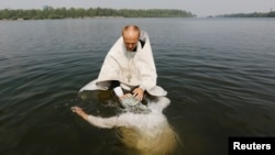 An Orthodox priest baptizes a woman in the Yenisei River during a ceremony marking the Christianization of the country in Krasnoyarsk.
