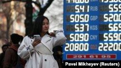 Прохожая рядом с табло с курсом покупки и продажи иностранной валюты. Алматы, 9 марта 2020 года.