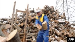 A man piles chopped wood by the roadside outside Sarajevo.