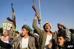 Huthi fighters brandish their weapons during a protest following U.S. and British strikes, in the Huthi-controlled Yemeni capital, Sanaa, on January 12.