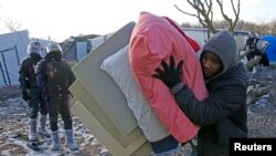 Мигрант несет постельные принадлежности в лагере в городе Кале. 7 марта 2016 года.
