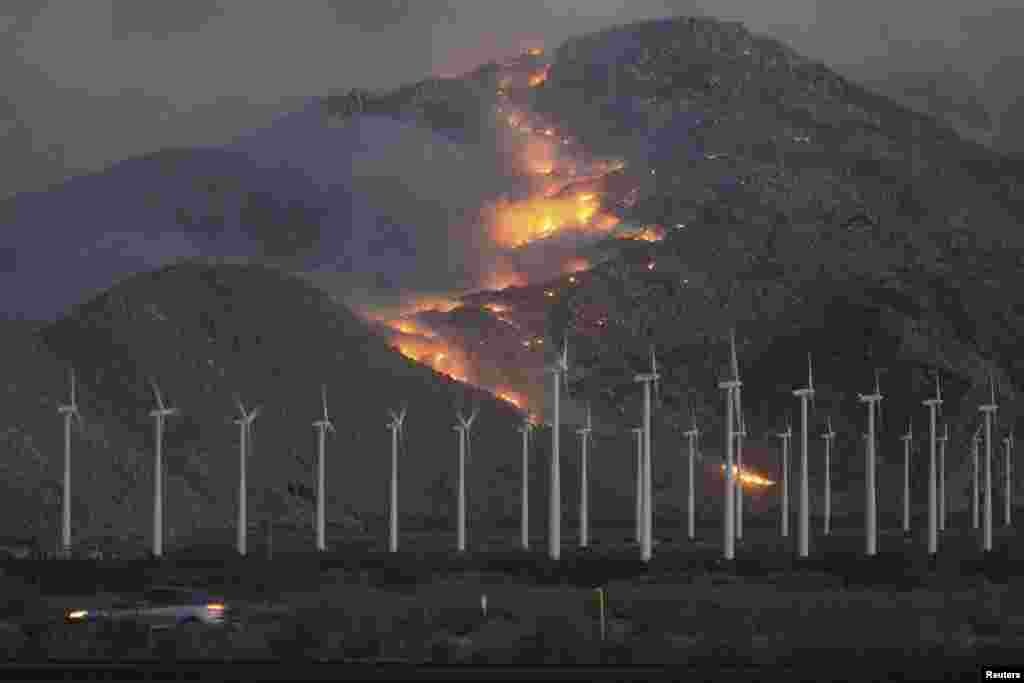 Wind turbines against a backdrop of wildfires, fanned by high winds, spreading up the slopes of the San Jacinto Mountains in southern California. (Reuters/David McNew)