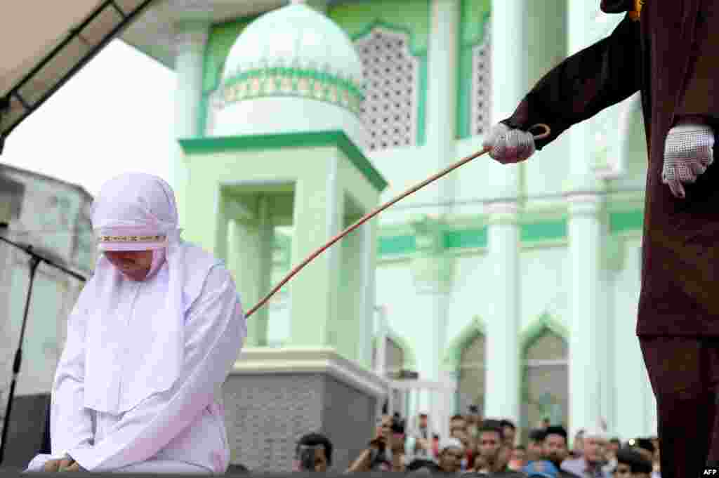 A 20-year old Muslim woman gets caned after being caught in close proximity to her boyfriend in Banda Aceh, Indonesia. Aceh is the only province in the predominantly Muslim country that applies Shari'a law. Public canings for breaches of Islamic code happen on a regular basis and often attract huge crowds. (AFP/Chaideer Mahyuddin)