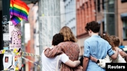 People embrace near the police line following a deadly shooting at the London Pub, a popular gay bar and nightclub in central Oslo, in June 2022. 