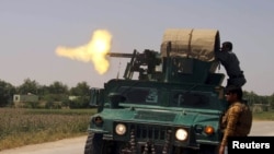 Afghan security forces fire from an armored vehicle during a battle with Taliban insurgents in Kunduz Province on May 3.