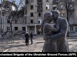 A March 2 photo showing locals looking at a building near the lovers' monument that was recently damaged by a Russian strike.