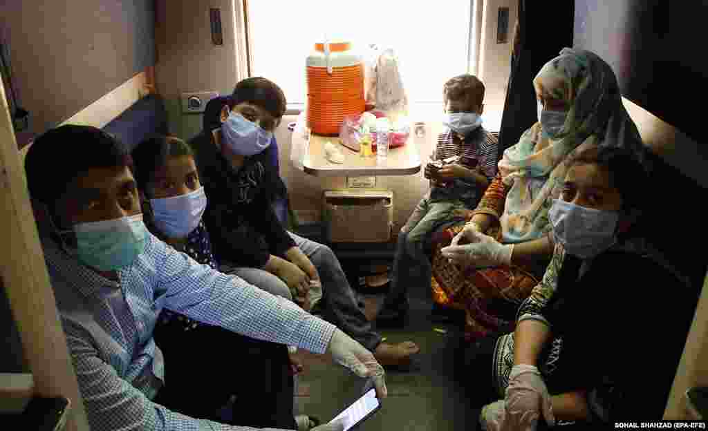 Masked passengers in Rawalpindi board a train on May 20.&nbsp;Authorities resumed railway service in Pakistan ahead of Eid al-Fitr after a two-month suspension.